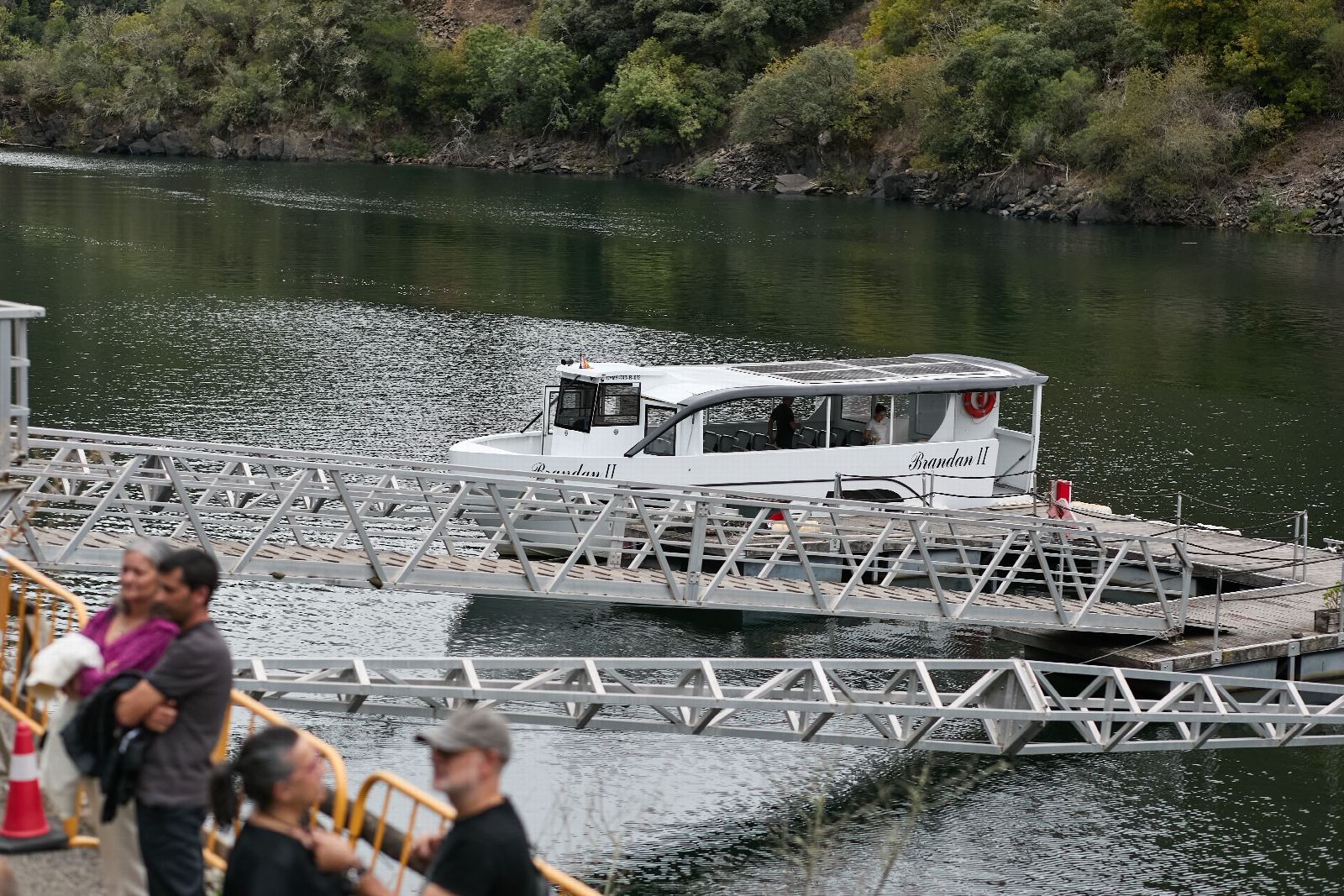 Xente no peirao, co catamarán atracado no río